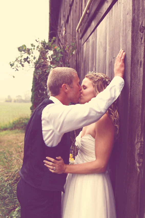 Das Brautpaar vor einem verwitterten Scheunentor